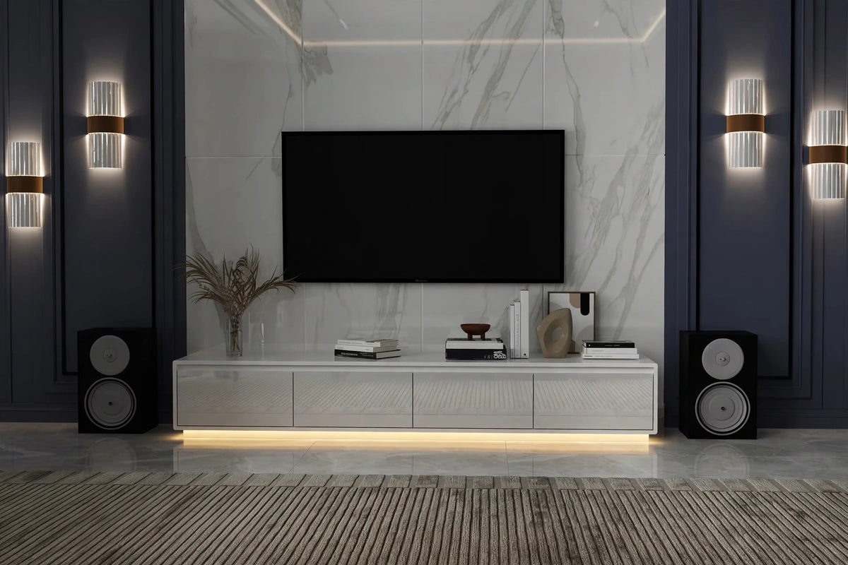 Modern white glossy floating TV console with LED base lighting in luxury dark-toned living room with marble wall and speakers