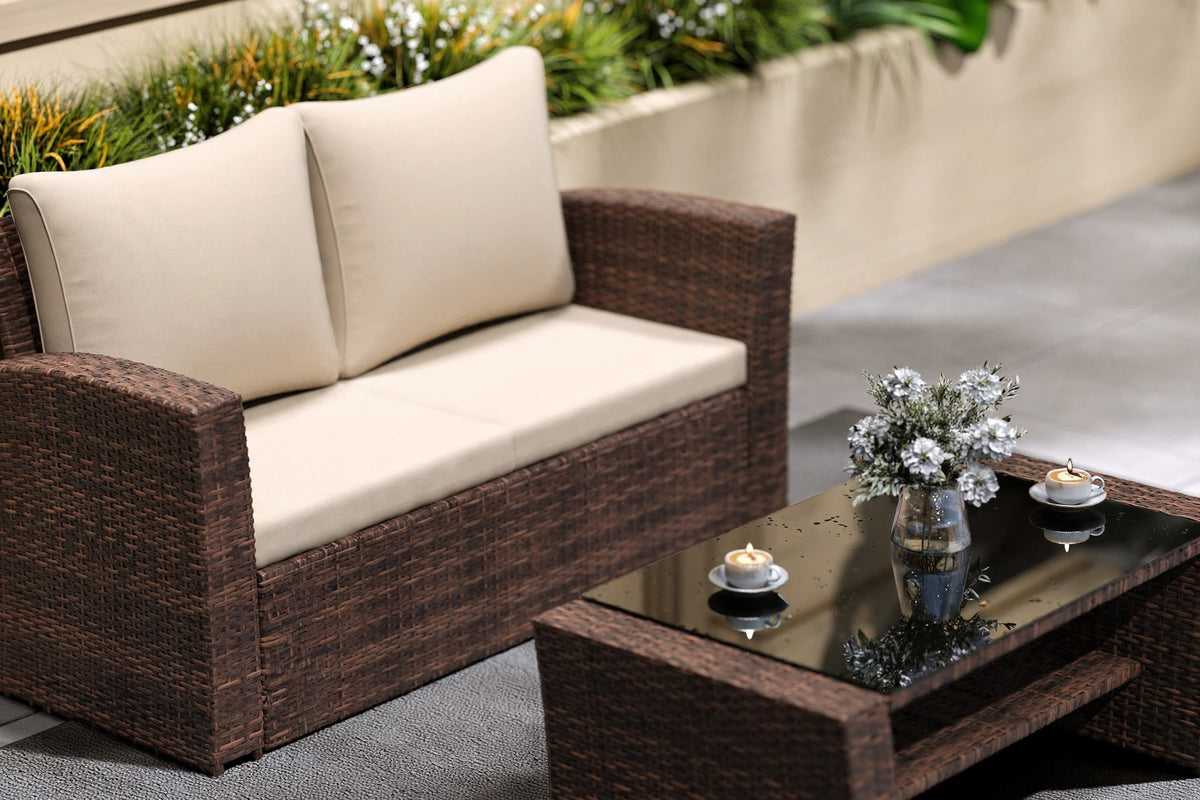 Close-up of espresso brown hand-woven PE rattan loveseat with cream cushions and tempered glass coffee table styled with candles and flowers
